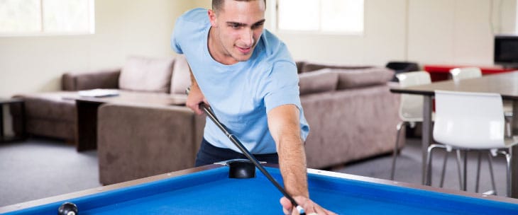 young male in blue shirt playing pool